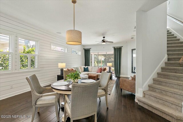 dining room featuring dark wood-type flooring, stairway, and wooden walls