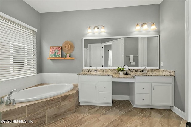 bathroom with a wealth of natural light, double vanity, a sink, and a bath