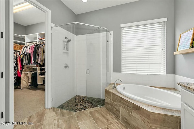 full bath with a stall shower, a garden tub, and a walk in closet