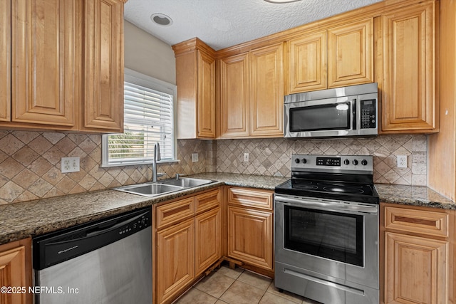 kitchen with tasteful backsplash, stainless steel appliances, a textured ceiling, a sink, and light tile patterned flooring