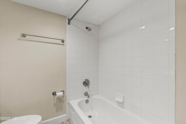 bathroom featuring bathing tub / shower combination, toilet, and baseboards