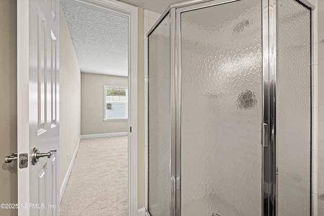 bathroom with baseboards, a textured ceiling, and a shower stall