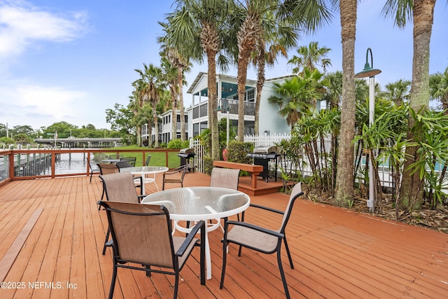 wooden terrace with a water view, area for grilling, and outdoor dining space