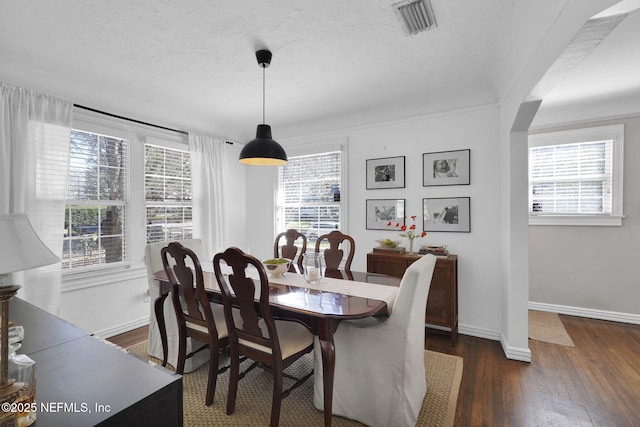 dining area with dark wood-style floors, a textured ceiling, visible vents, and baseboards