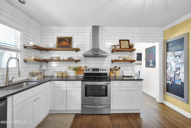 kitchen featuring stainless steel appliances, a sink, wall chimney range hood, open shelves, and dark countertops