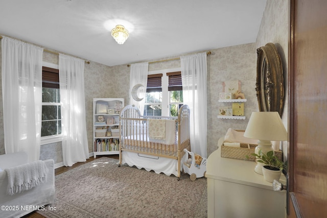 bedroom featuring baseboards, wood finished floors, and wallpapered walls