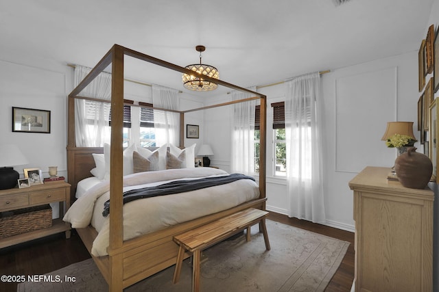 bedroom with a chandelier and dark wood-style flooring