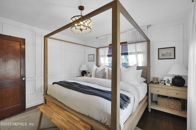 bedroom featuring a decorative wall, an inviting chandelier, and wood finished floors