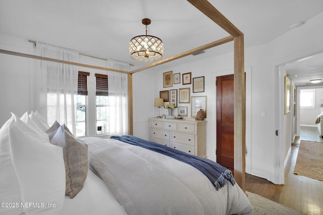 bedroom with wood finished floors, visible vents, and a notable chandelier