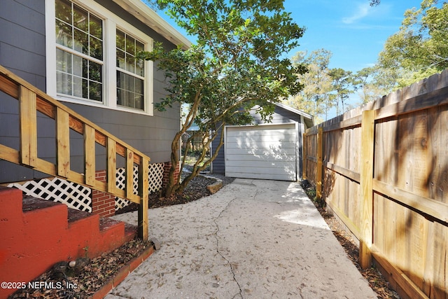 exterior space featuring an outbuilding, fence, driveway, and a detached garage