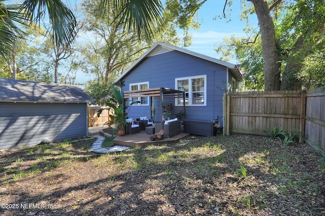 rear view of property with a fenced backyard, an outdoor living space, and an outbuilding