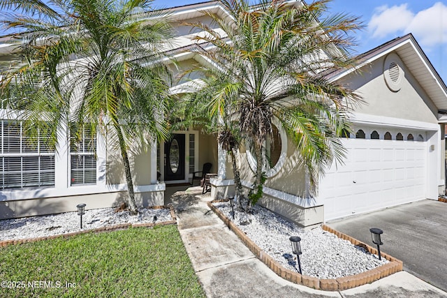 view of front facade featuring driveway, a porch, an attached garage, and stucco siding