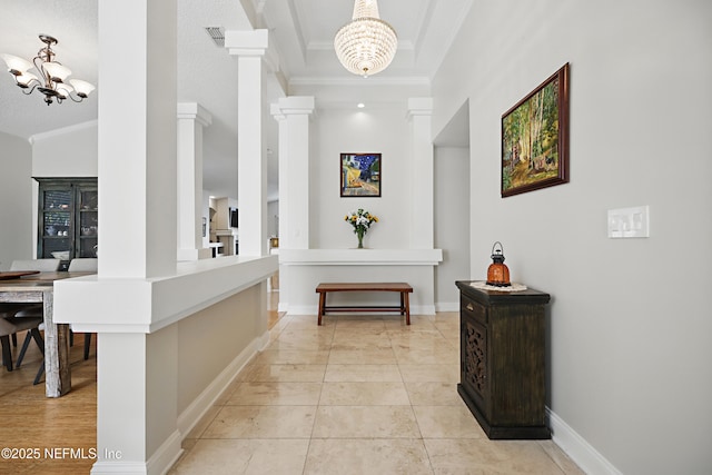 hall featuring ornate columns, visible vents, an inviting chandelier, ornamental molding, and baseboards