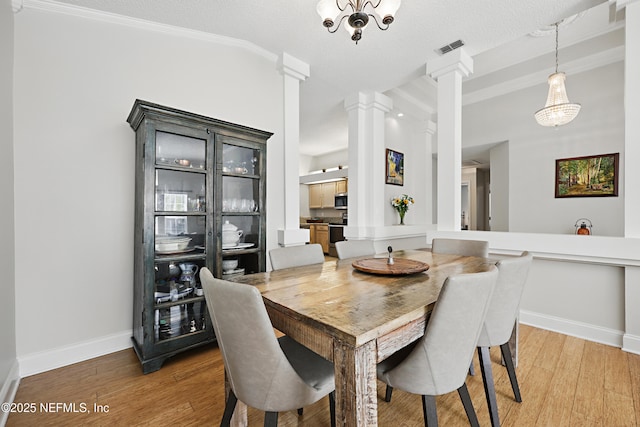 dining room with baseboards, visible vents, decorative columns, and light wood finished floors