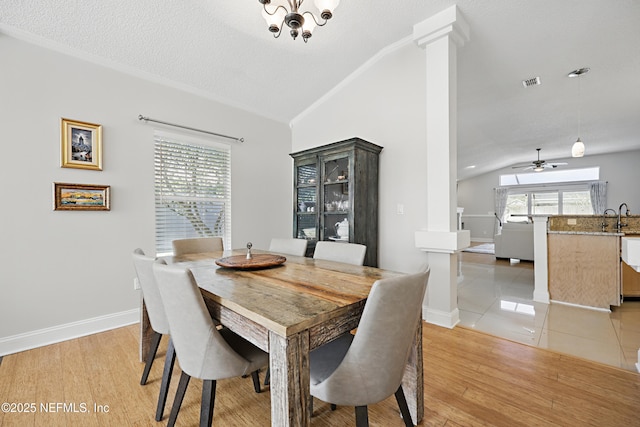 dining room with light wood-type flooring, lofted ceiling, visible vents, and decorative columns