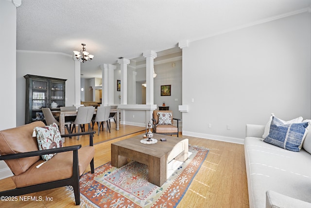 living room featuring light wood-style floors, lofted ceiling, a notable chandelier, and decorative columns