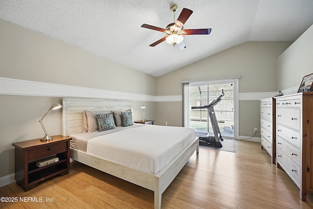 bedroom featuring light wood finished floors, ceiling fan, access to outside, vaulted ceiling, and a textured ceiling