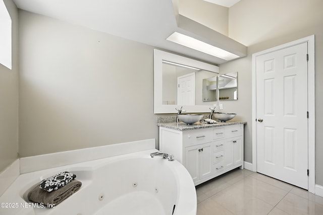 bathroom with double vanity, a jetted tub, tile patterned flooring, and a sink