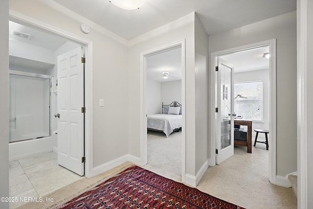 hallway featuring carpet floors, tile patterned flooring, visible vents, and baseboards