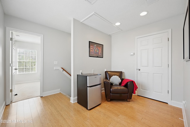 living area with light wood finished floors, an upstairs landing, attic access, and baseboards