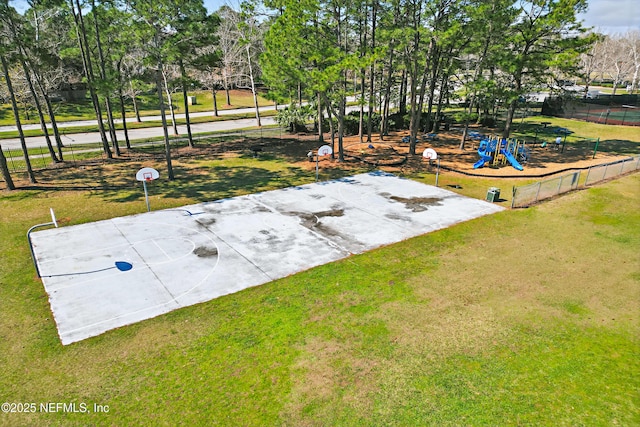 view of yard with playground community, fence, and community basketball court