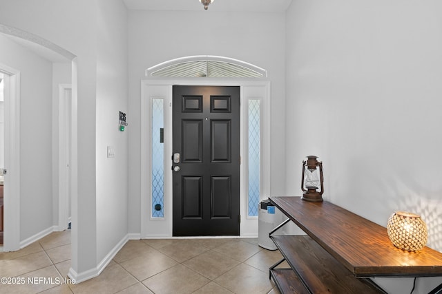 foyer with light tile patterned flooring, baseboards, and arched walkways