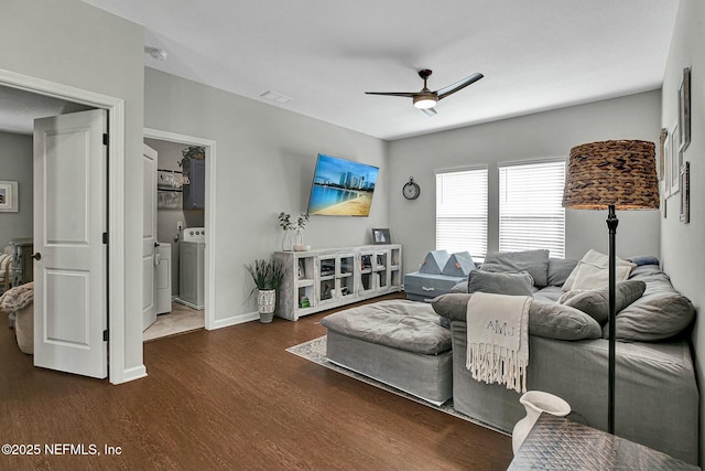 living room with dark wood-style floors, visible vents, ceiling fan, separate washer and dryer, and baseboards