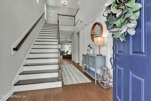 foyer with stairs, baseboards, a high ceiling, and wood finished floors