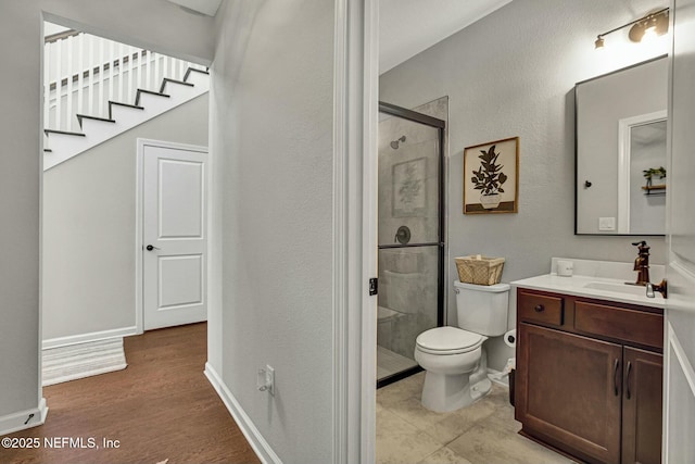 bathroom featuring a stall shower, baseboards, toilet, wood finished floors, and vanity