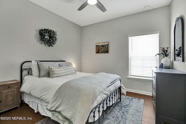 bedroom with dark wood-type flooring, a ceiling fan, and baseboards