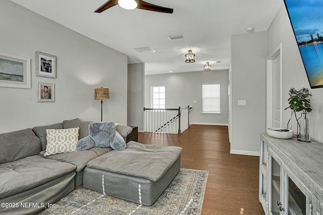 living area featuring dark wood-style floors, baseboards, visible vents, and a ceiling fan