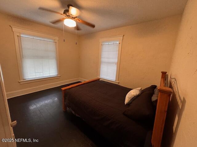 bedroom featuring ceiling fan, a textured ceiling, baseboards, and wood finished floors