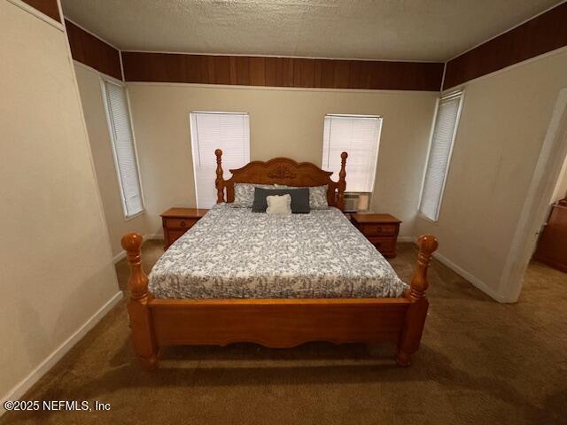 bedroom featuring a textured ceiling, dark carpet, and baseboards