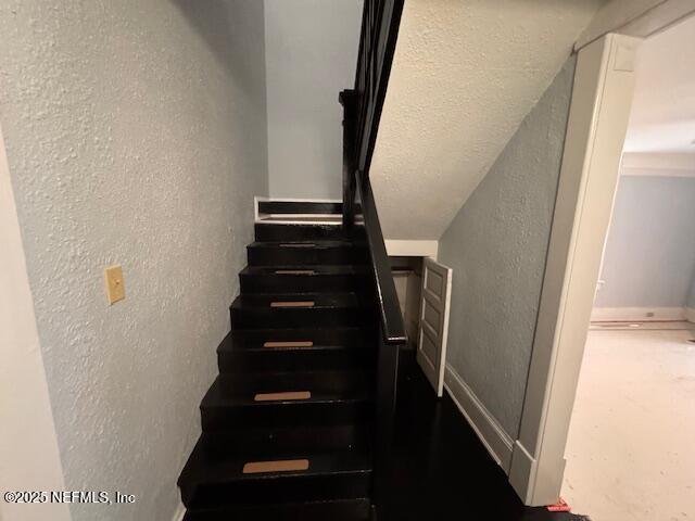 staircase with a textured wall and baseboards