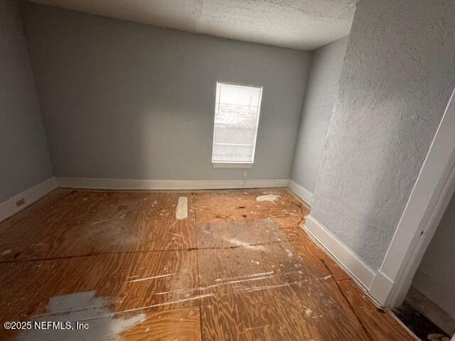 spare room with baseboards and a textured ceiling