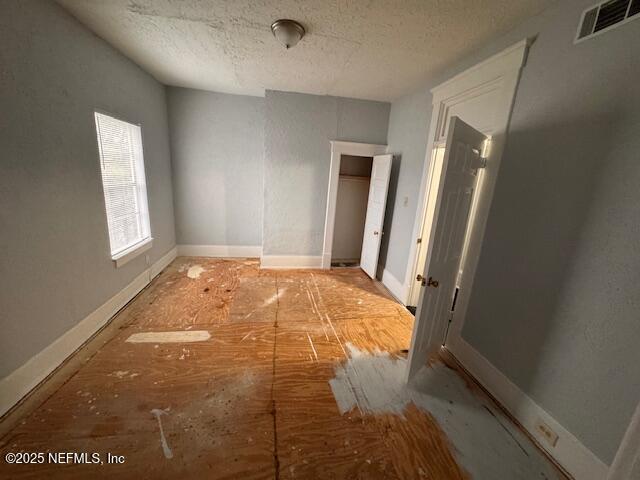 interior space with visible vents, a textured ceiling, and baseboards