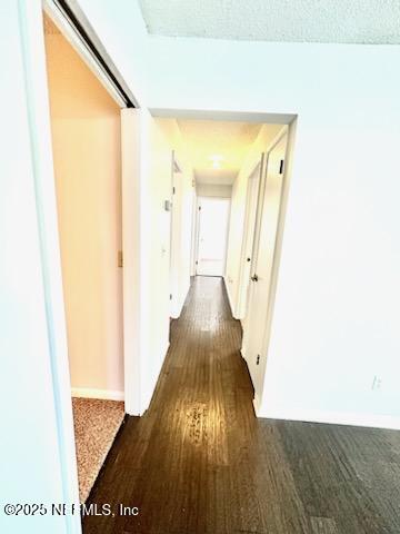 hall with dark wood-type flooring and a textured ceiling