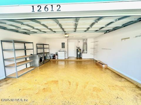 garage with water heater, washer / clothes dryer, and baseboards