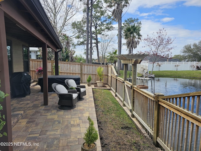 view of patio with a water view, outdoor lounge area, a fenced backyard, and area for grilling