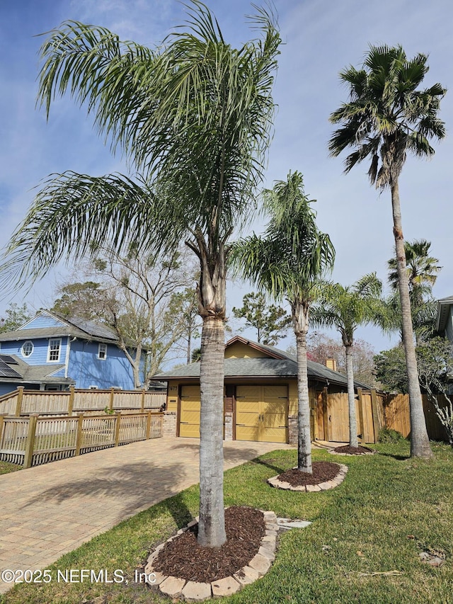 view of front of home with a garage, decorative driveway, a front yard, and fence