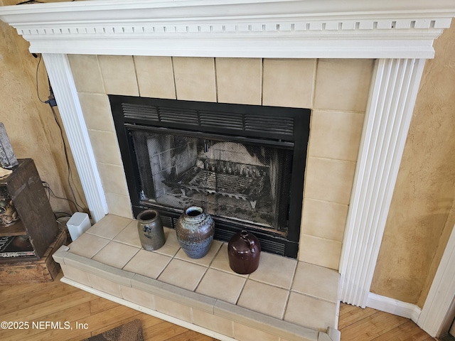 room details with wood finished floors and a tile fireplace