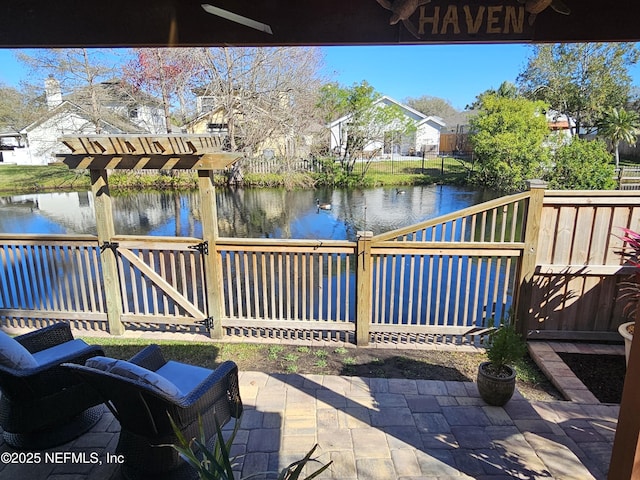 view of patio / terrace featuring a water view and fence