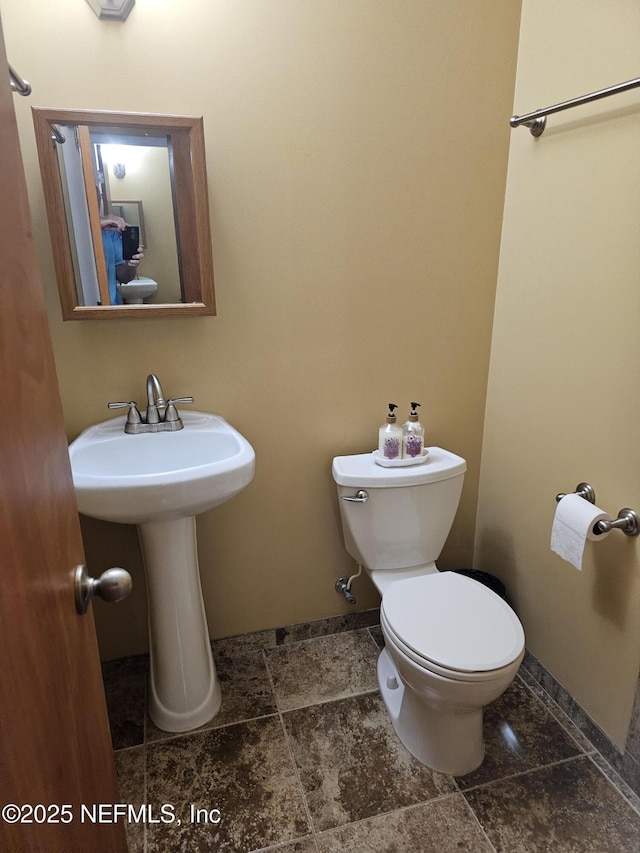 half bath featuring a sink, toilet, and baseboards