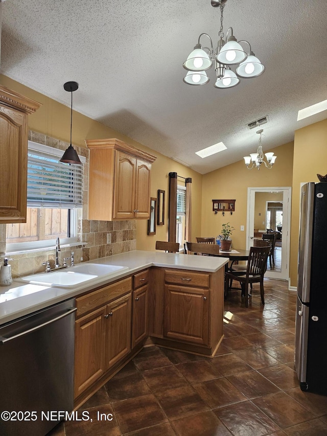 kitchen featuring a peninsula, appliances with stainless steel finishes, a chandelier, and a sink