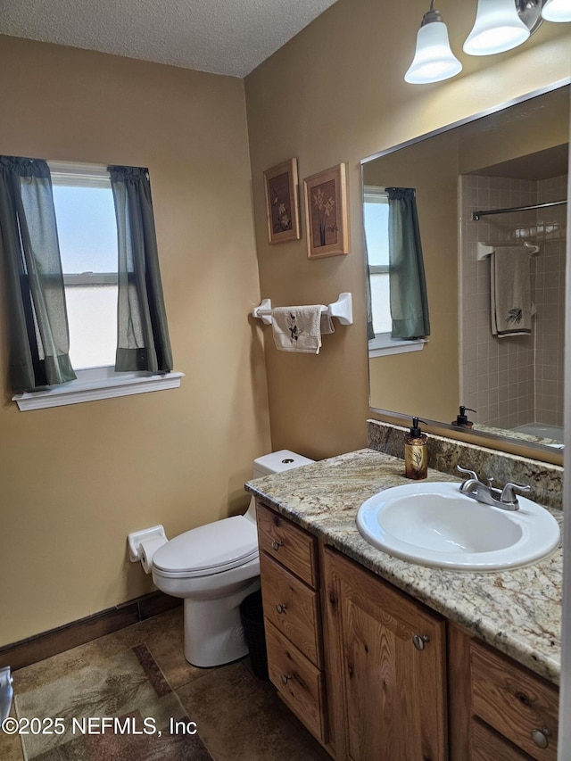 full bathroom featuring a shower, toilet, vanity, a textured ceiling, and baseboards