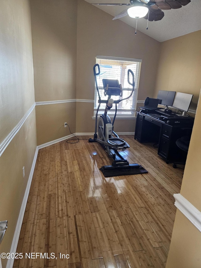 exercise area featuring ceiling fan, baseboards, vaulted ceiling, and wood finished floors