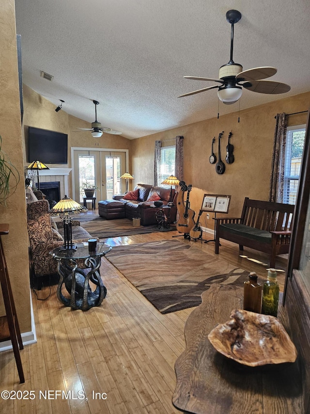 living room with lofted ceiling, hardwood / wood-style flooring, plenty of natural light, and visible vents