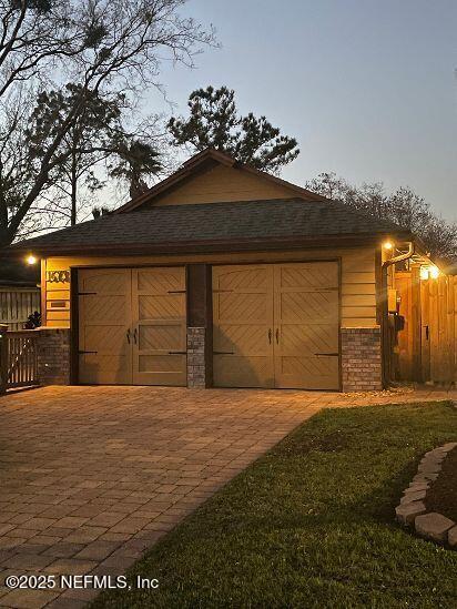 garage featuring decorative driveway and fence