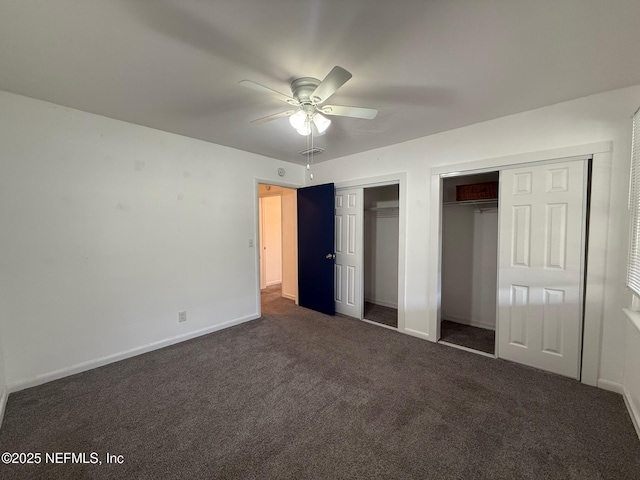 unfurnished bedroom featuring a ceiling fan, baseboards, dark colored carpet, and two closets