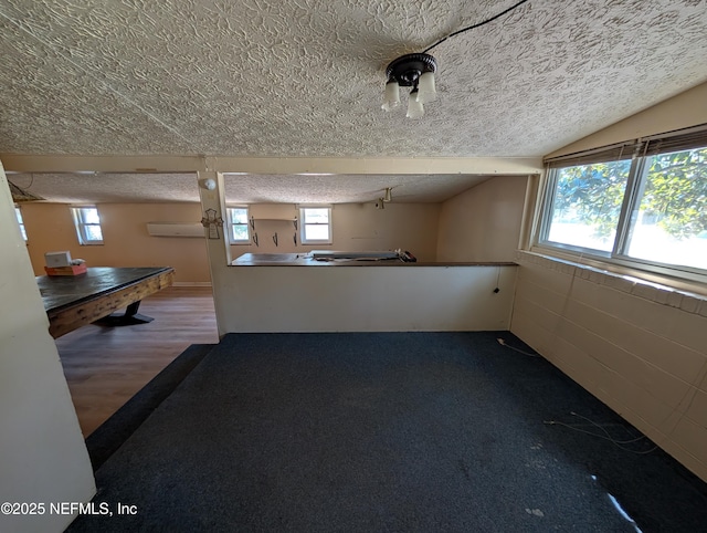 kitchen with lofted ceiling, a healthy amount of sunlight, a textured ceiling, and a wall mounted AC